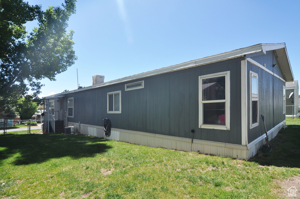 View of home's exterior featuring central AC unit and a lawn