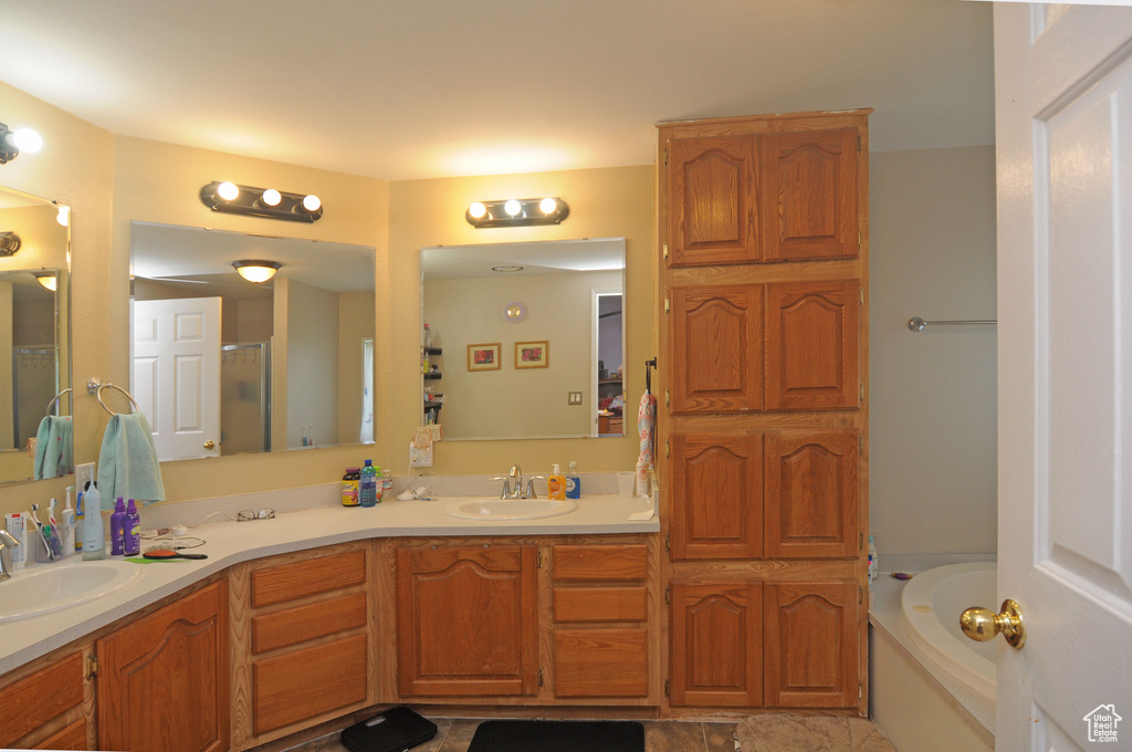 Bathroom with vanity with extensive cabinet space, double sink, tile flooring, and a bathing tub