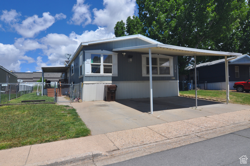 Manufactured / mobile home with a front yard and a carport