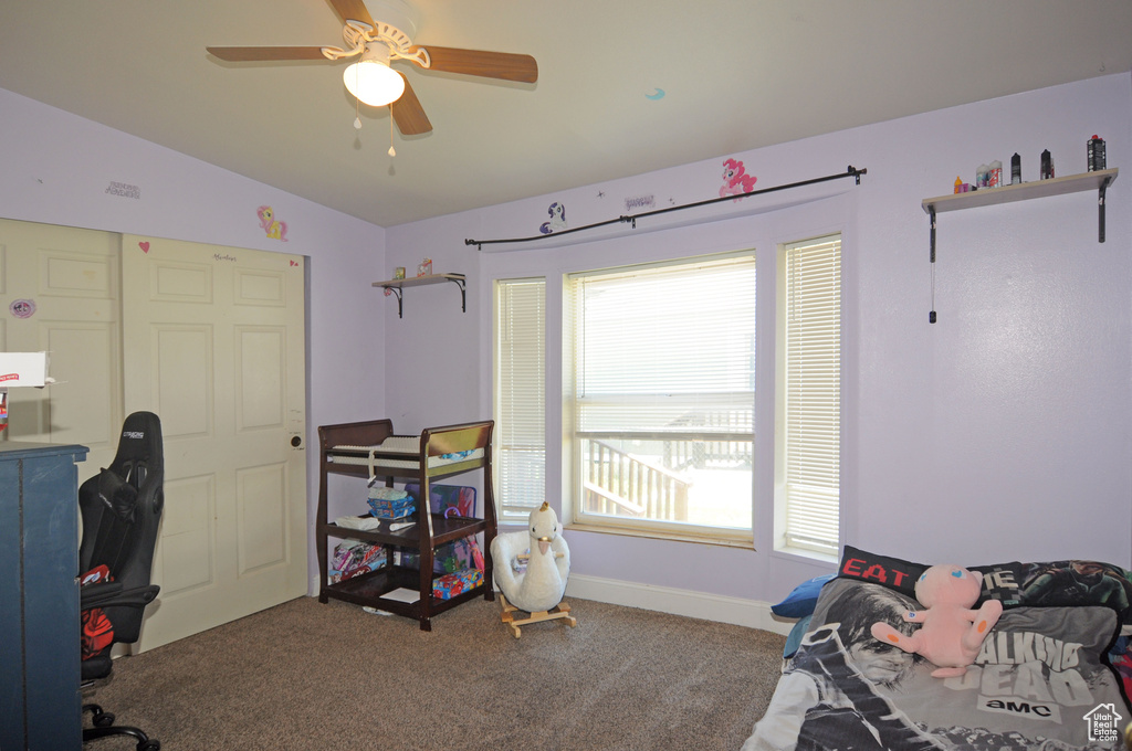 Carpeted bedroom featuring multiple windows, vaulted ceiling, and ceiling fan