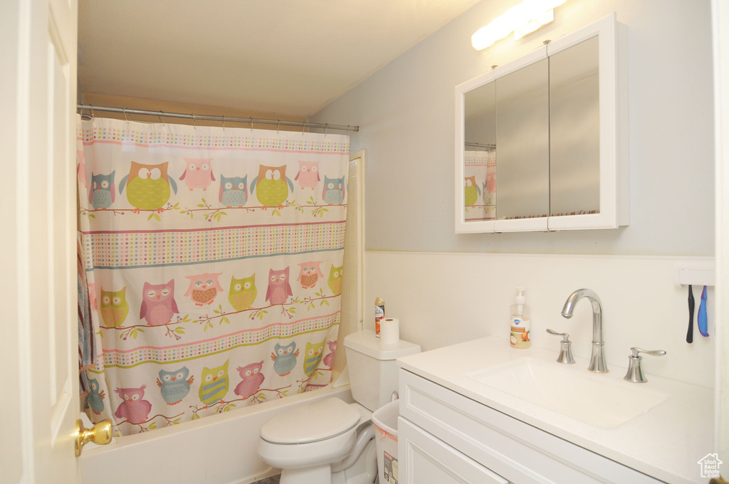 Full bathroom featuring shower / bathtub combination with curtain, vanity, and toilet