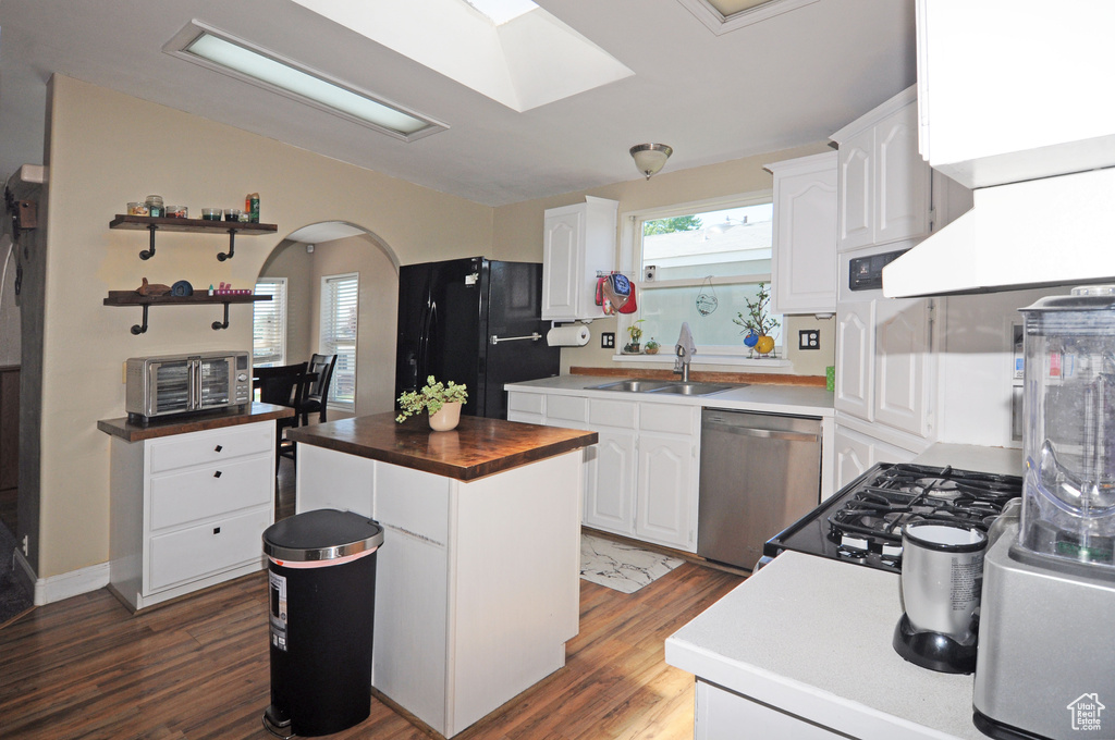 Kitchen featuring dark hardwood / wood-style floors, a kitchen island, white cabinetry, stainless steel dishwasher, and sink