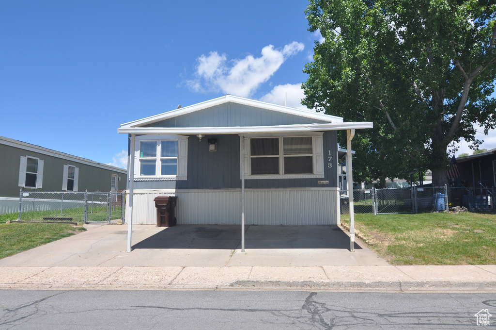 Manufactured / mobile home featuring a carport and a front yard