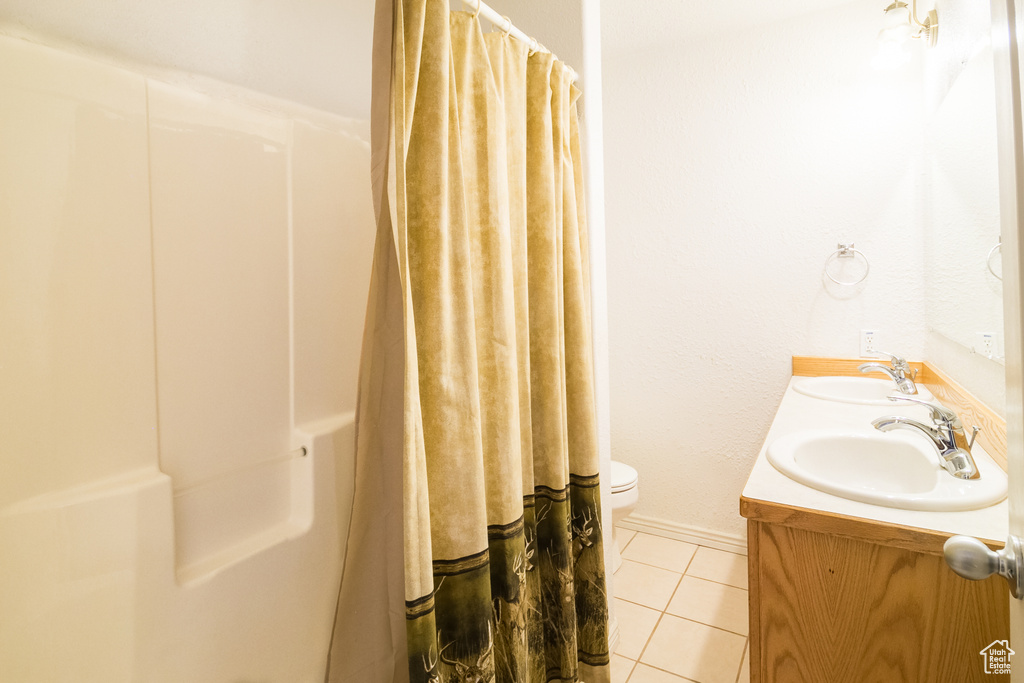 Bathroom with tile flooring, dual vanity, and toilet