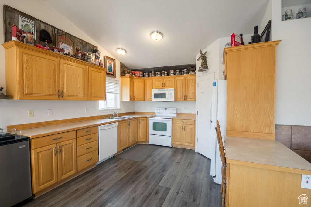 Kitchen featuring sink, vaulted ceiling, white appliances, and dark hardwood / wood-style flooring