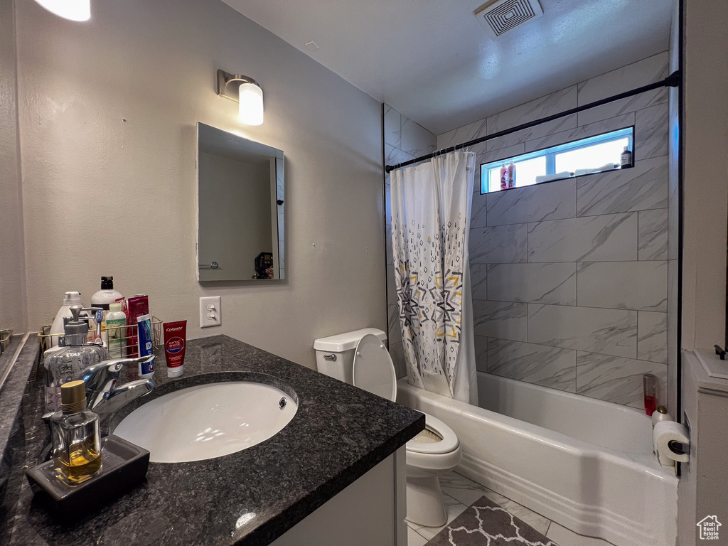 Full bathroom featuring tile flooring, vanity, toilet, and shower / tub combo