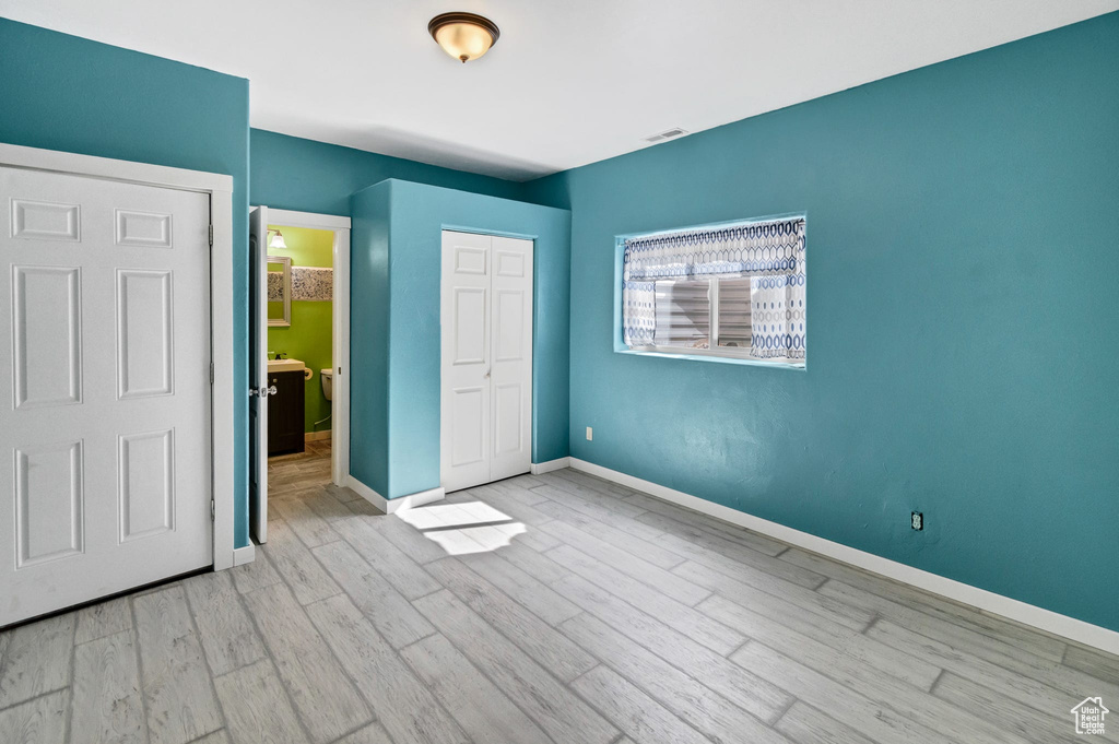 Unfurnished bedroom with visible vents, a closet, light wood-style flooring, and baseboards