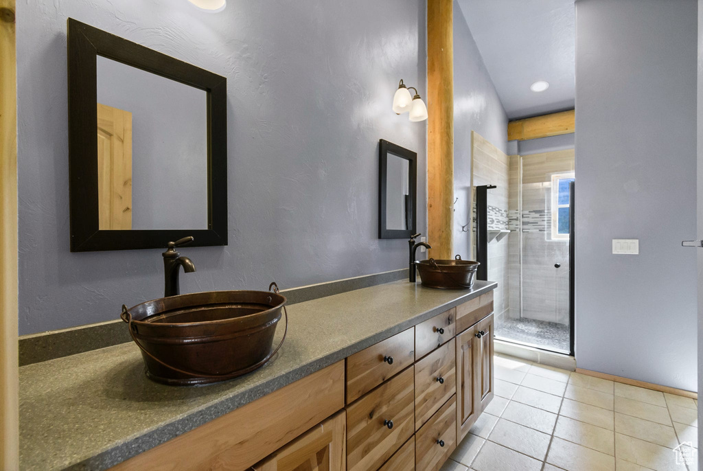 Bathroom featuring baseboards, double vanity, a sink, and tile patterned floors