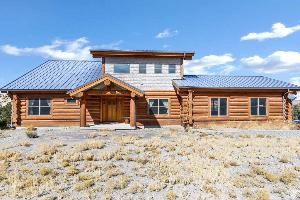 View of front of house with metal roof, log exterior, and a standing seam roof