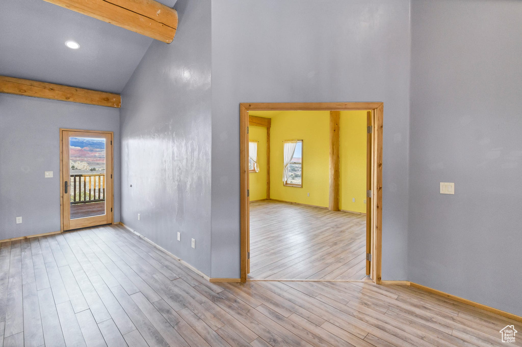 Spare room featuring a wealth of natural light, light wood-style flooring, and beamed ceiling