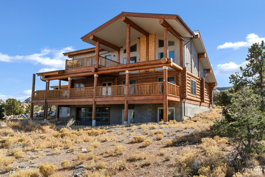 Back of property with log exterior and a balcony