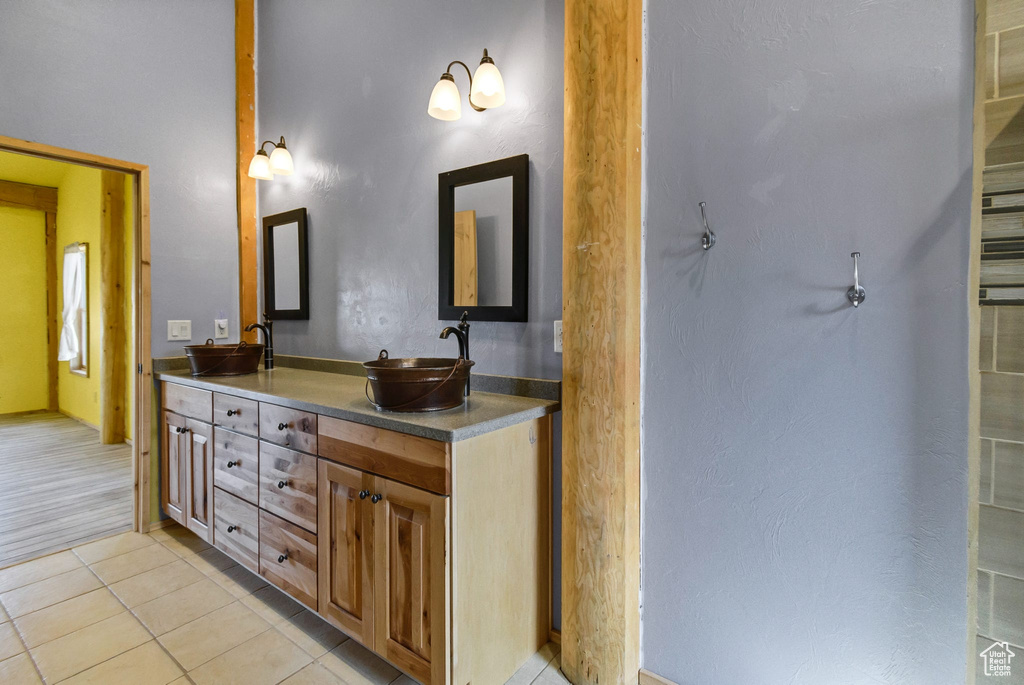 Bathroom with double vanity, a sink, and tile patterned floors