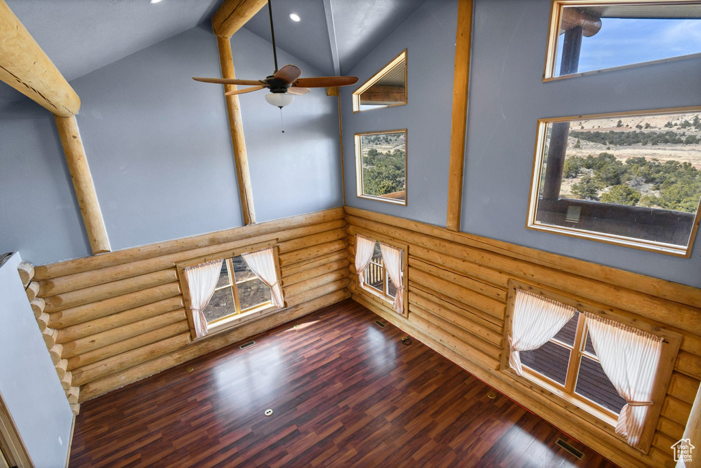 Empty room featuring high vaulted ceiling, a wealth of natural light, dark wood-style flooring, and beamed ceiling