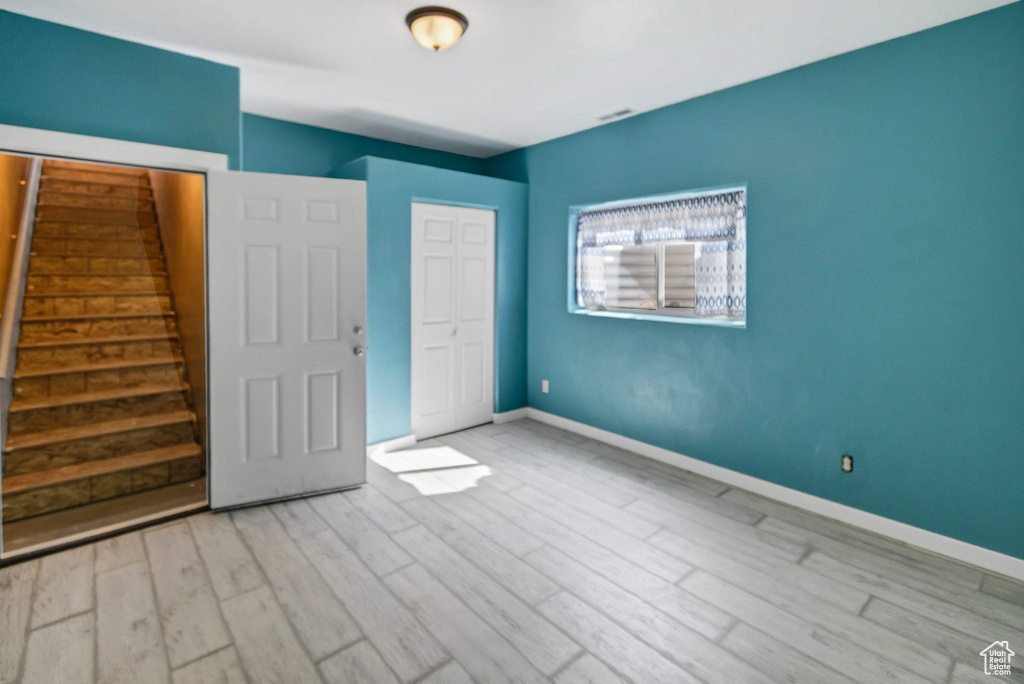 Unfurnished bedroom featuring light wood-style flooring, baseboards, and a closet