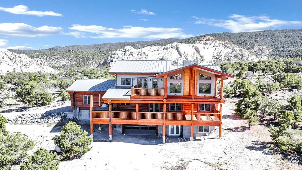 Snow covered house with a deck with mountain view, a standing seam roof, and metal roof