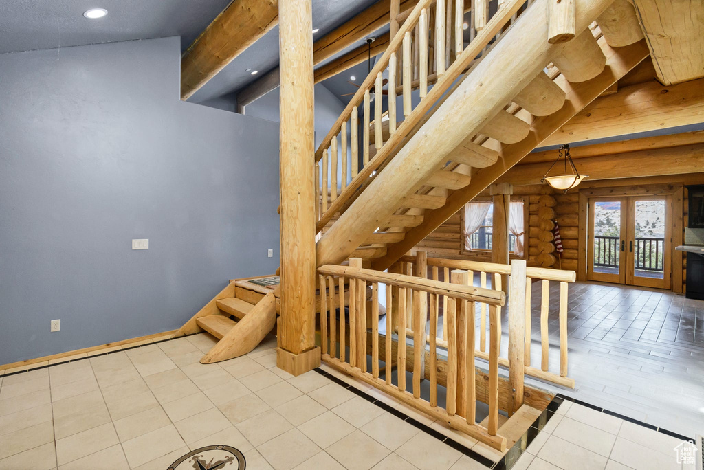 Stairway with baseboards, french doors, log walls, tile patterned floors, and beamed ceiling