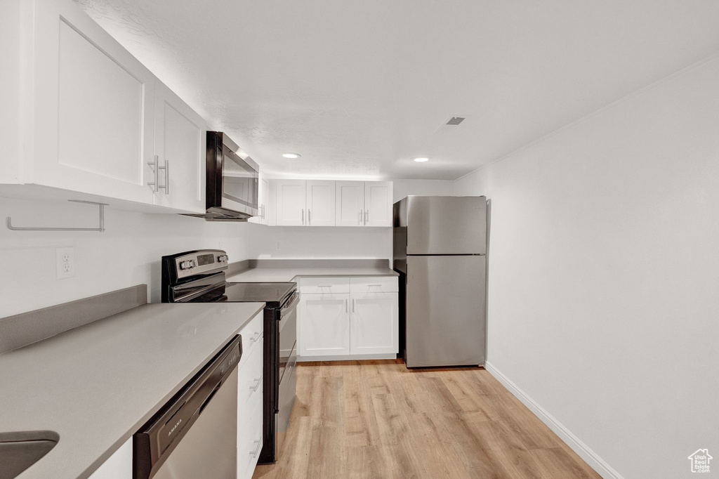 Kitchen featuring stainless steel appliances, white cabinetry, and light wood-type flooring
