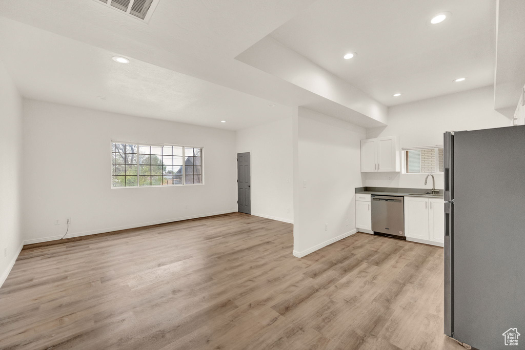 Kitchen featuring sink, stainless steel appliances, light wood-type flooring, and white cabinetry