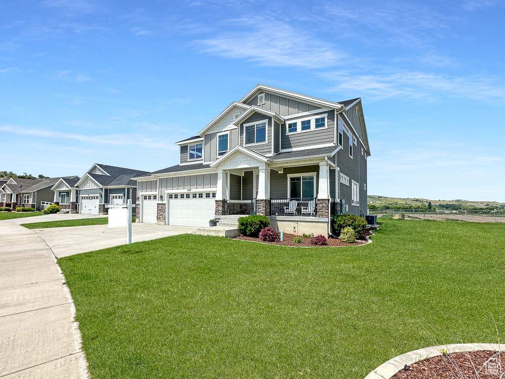 Craftsman inspired home featuring a front lawn, a porch, and a garage