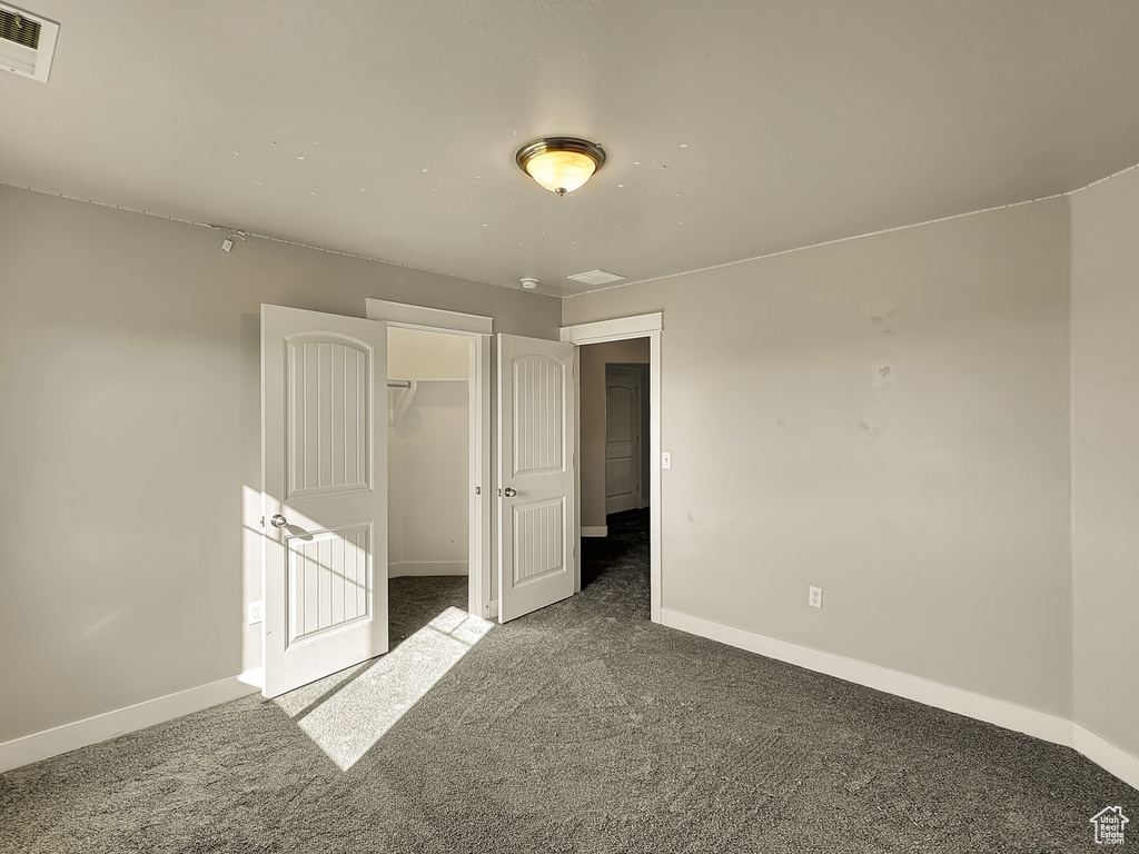 Unfurnished bedroom featuring a closet, carpet flooring, and a spacious closet