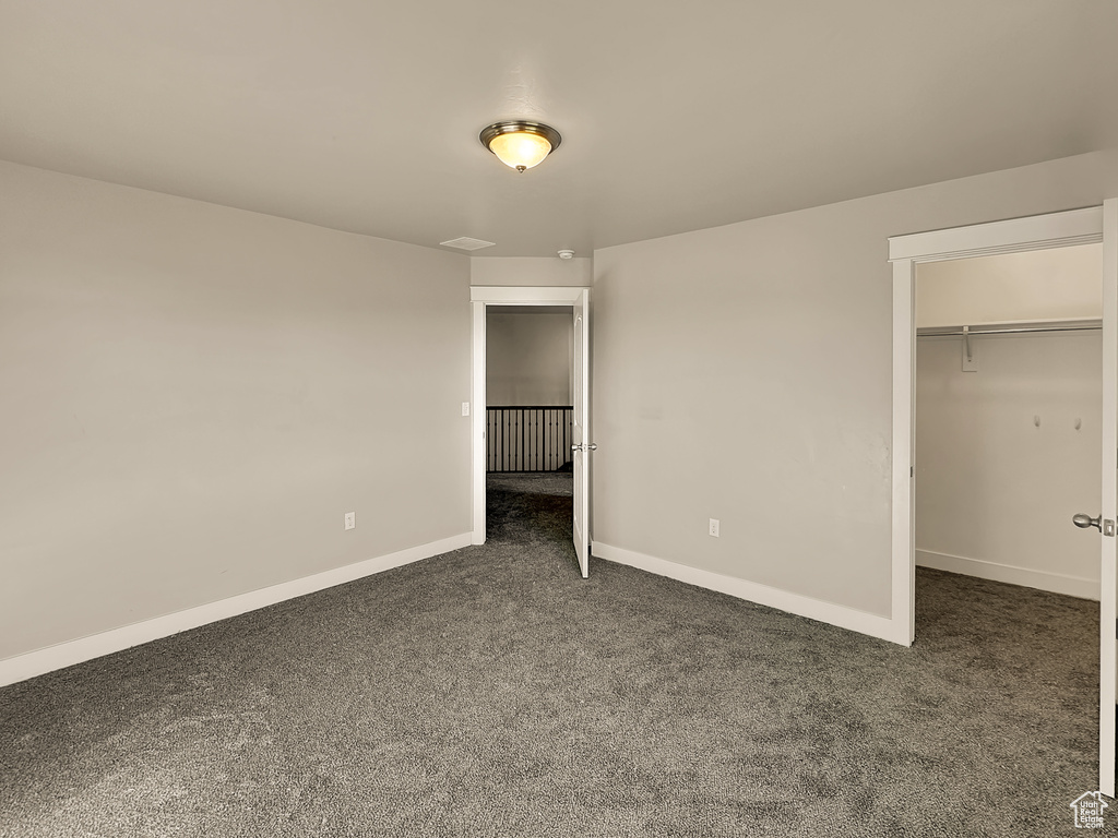 Unfurnished bedroom with a spacious closet, a closet, and carpet floors