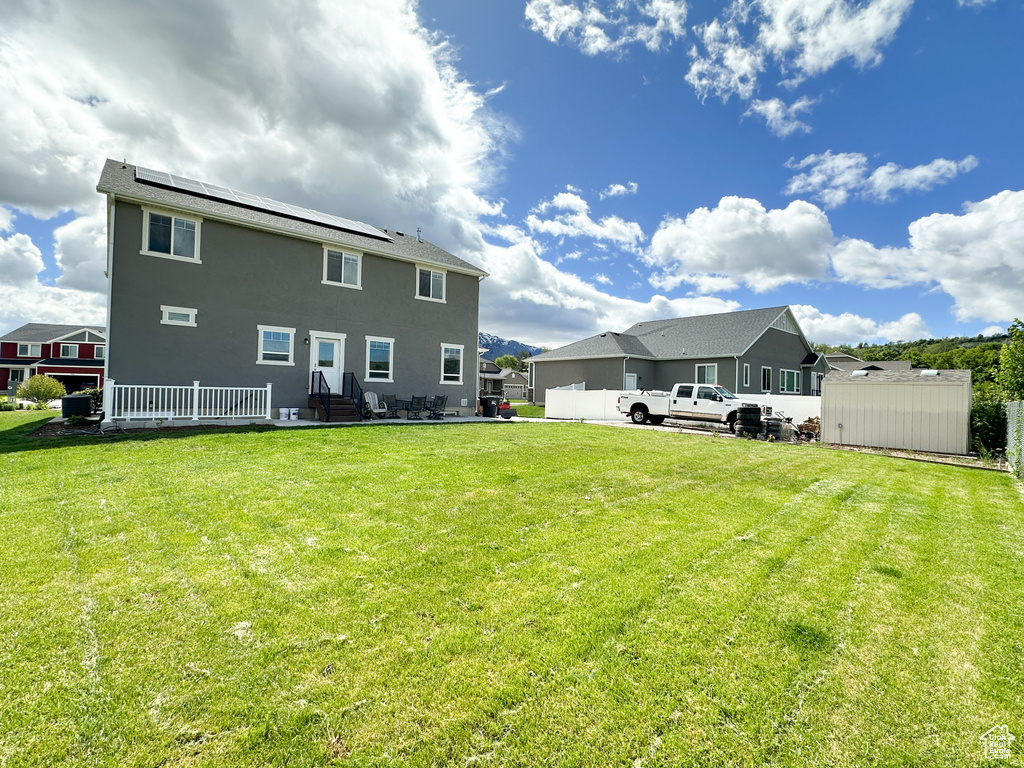 Back of house featuring a storage unit and a lawn