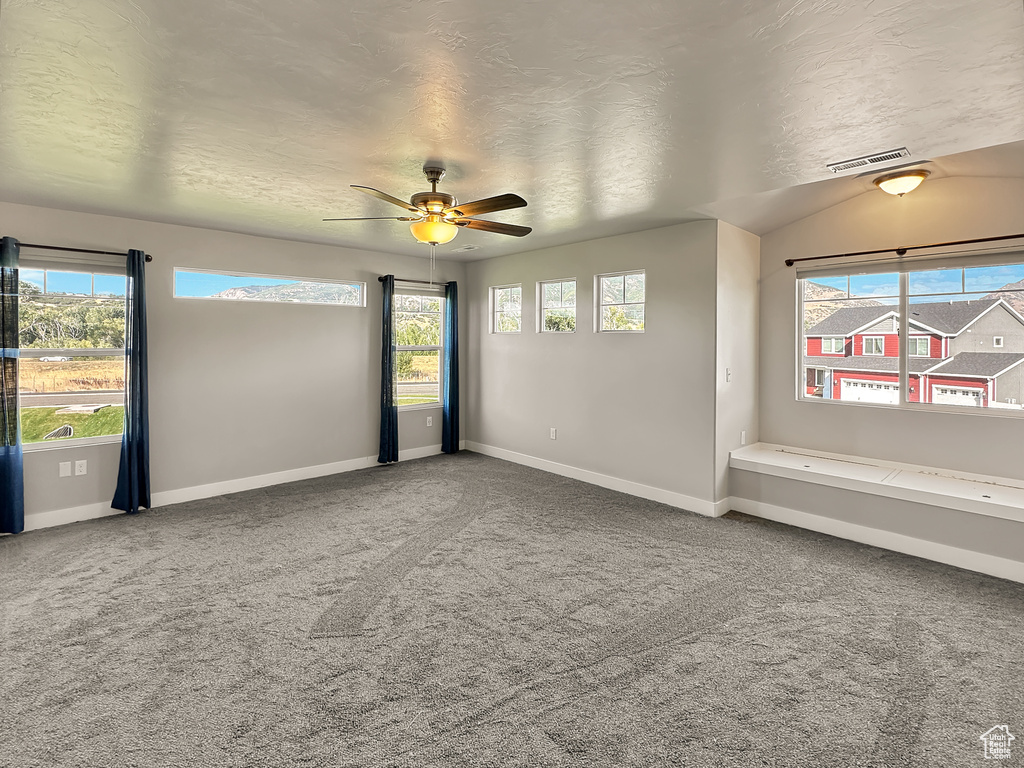 Carpeted empty room featuring a textured ceiling and ceiling fan