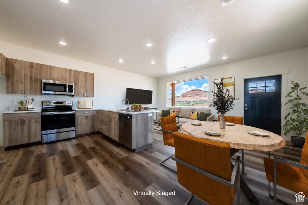 Kitchen featuring appliances with stainless steel finishes, dark hardwood / wood-style floors, kitchen peninsula, and sink