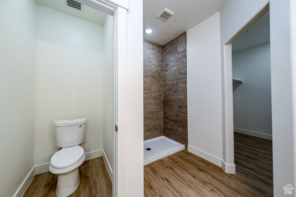 Bathroom featuring toilet, hardwood / wood-style floors, and tiled shower