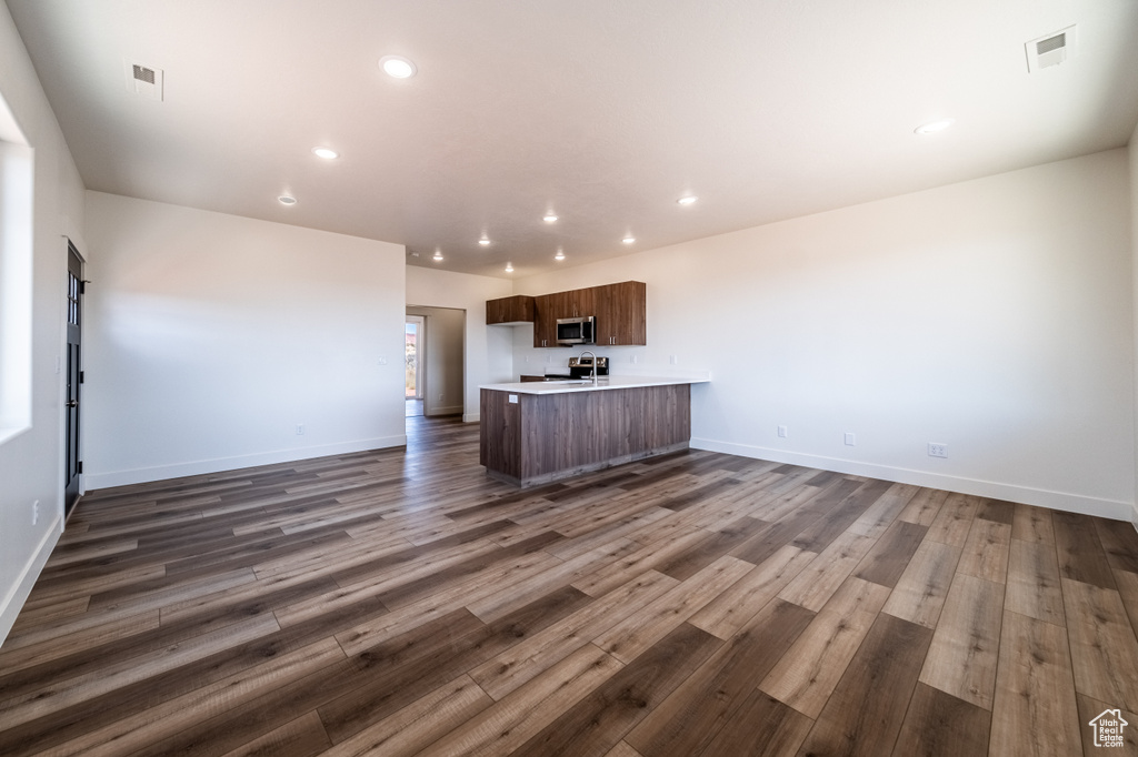 Unfurnished living room with a barn door and dark hardwood / wood-style flooring