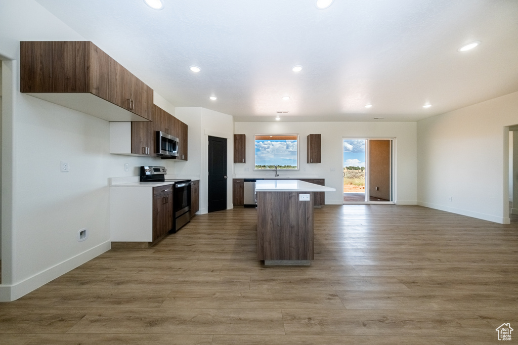 Kitchen with a center island, a breakfast bar area, stainless steel appliances, and light hardwood / wood-style floors