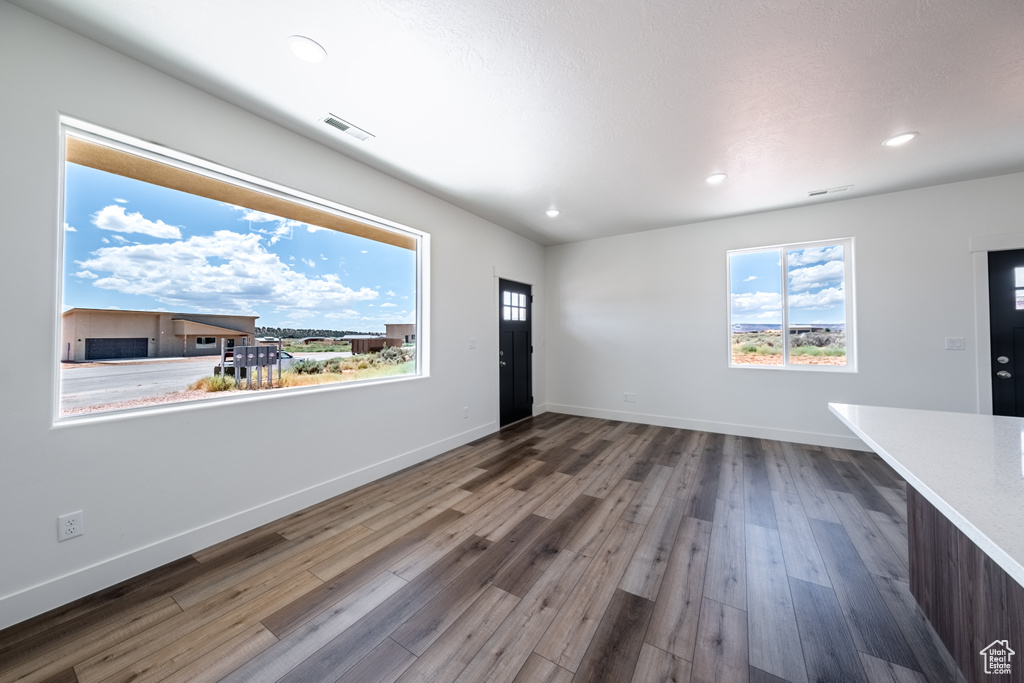 Unfurnished living room featuring hardwood / wood-style flooring and a wealth of natural light