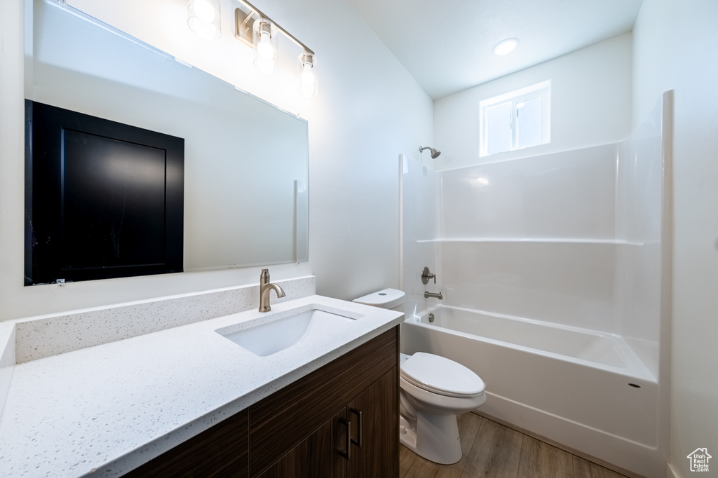 Full bathroom featuring vanity, toilet, hardwood / wood-style flooring, and washtub / shower combination