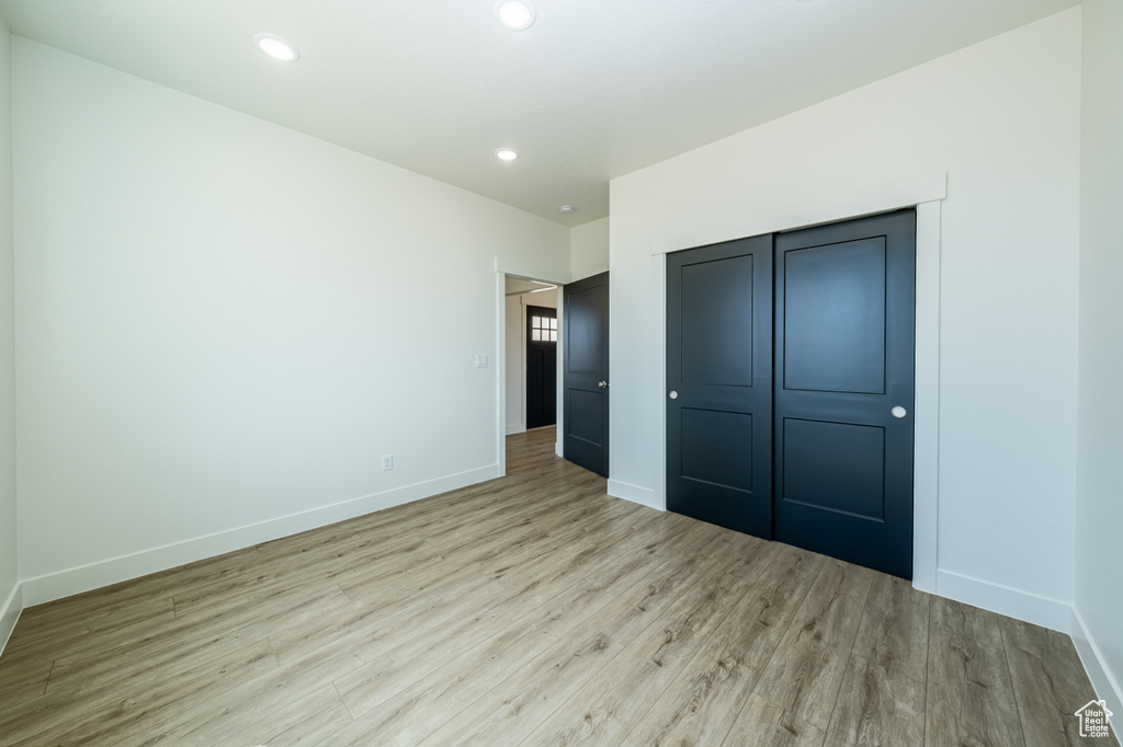 Unfurnished bedroom with light hardwood / wood-style flooring and a closet