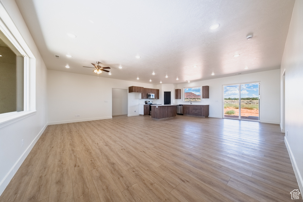 Unfurnished living room with ceiling fan and light hardwood / wood-style floors