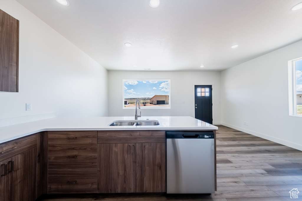 Kitchen featuring light hardwood / wood-style flooring, kitchen peninsula, stainless steel dishwasher, and sink