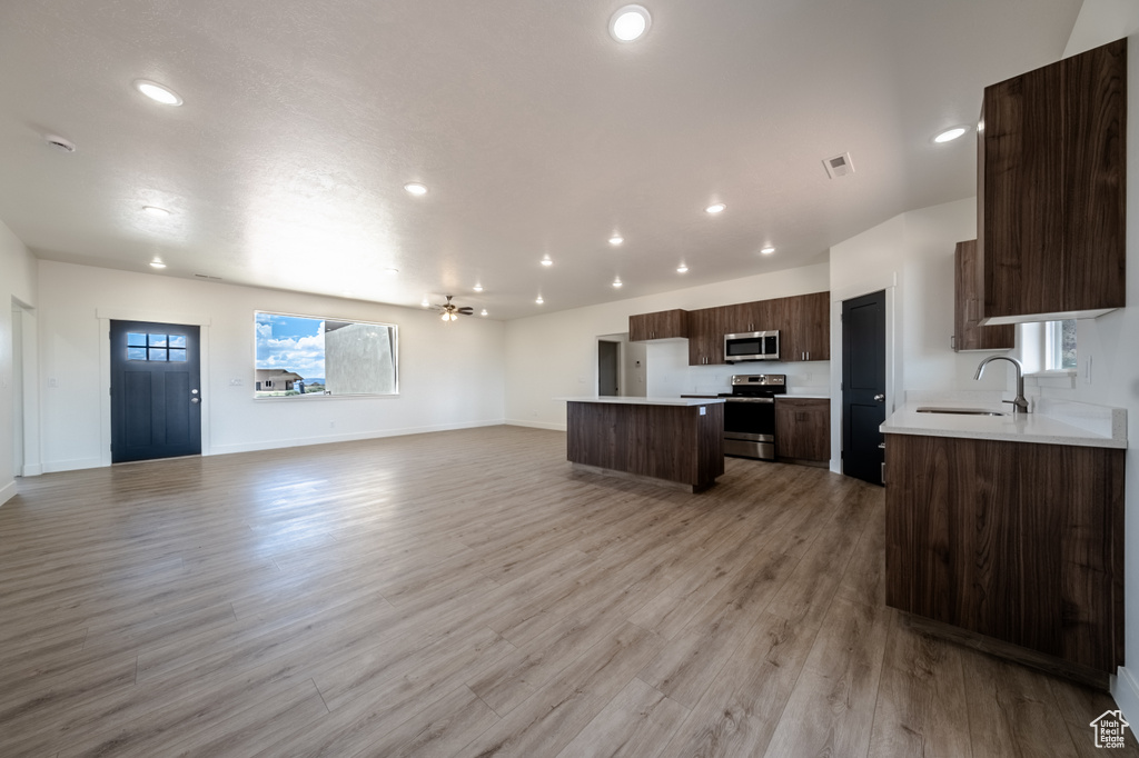 Kitchen featuring light wood-type flooring, stainless steel appliances, dark brown cabinetry, and sink