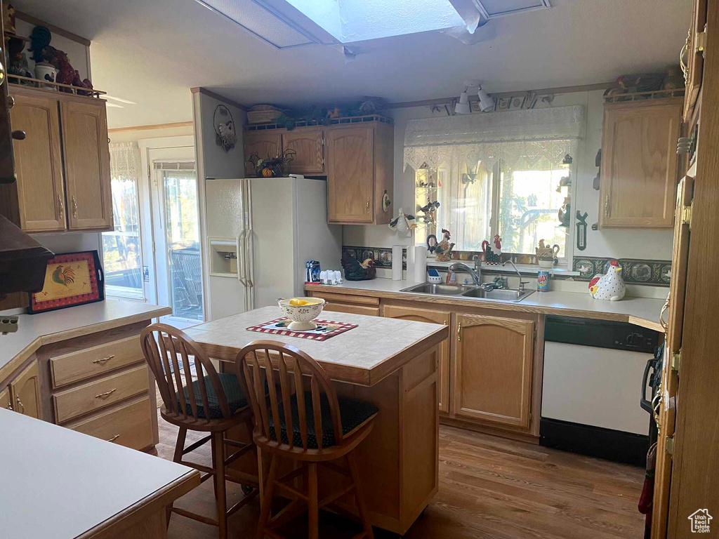 Kitchen with a center island, white appliances, hardwood / wood-style floors, sink, and a kitchen bar