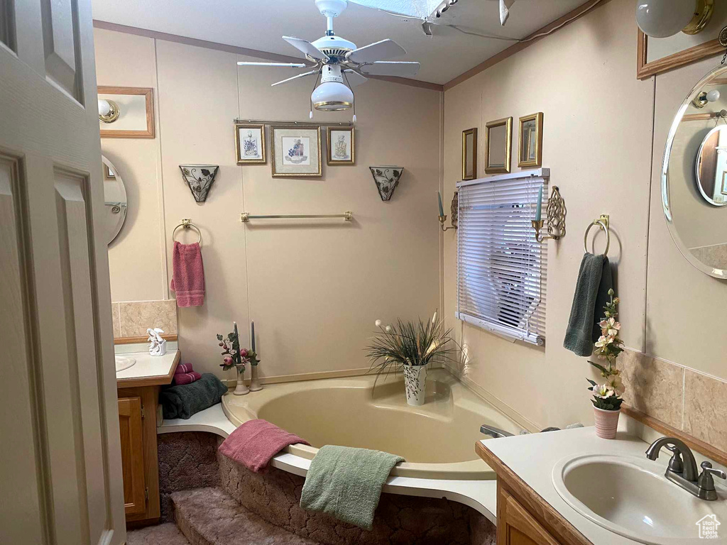 Bathroom featuring vanity, ceiling fan, a bathtub, and crown molding