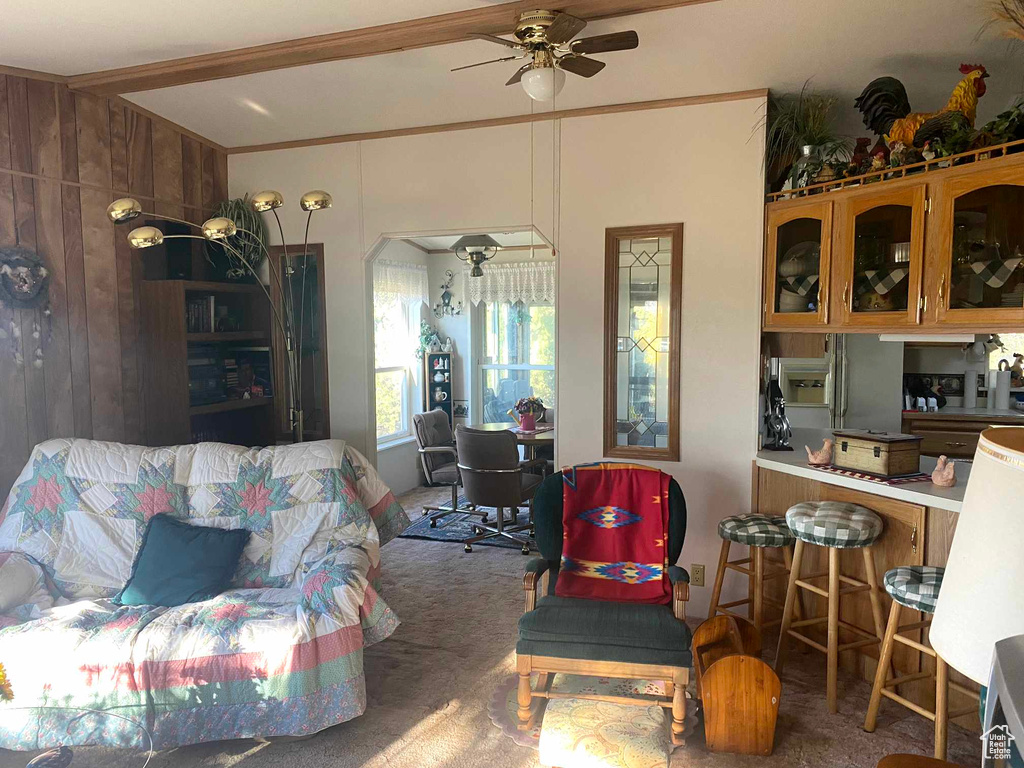 Carpeted living room featuring wood walls and ceiling fan