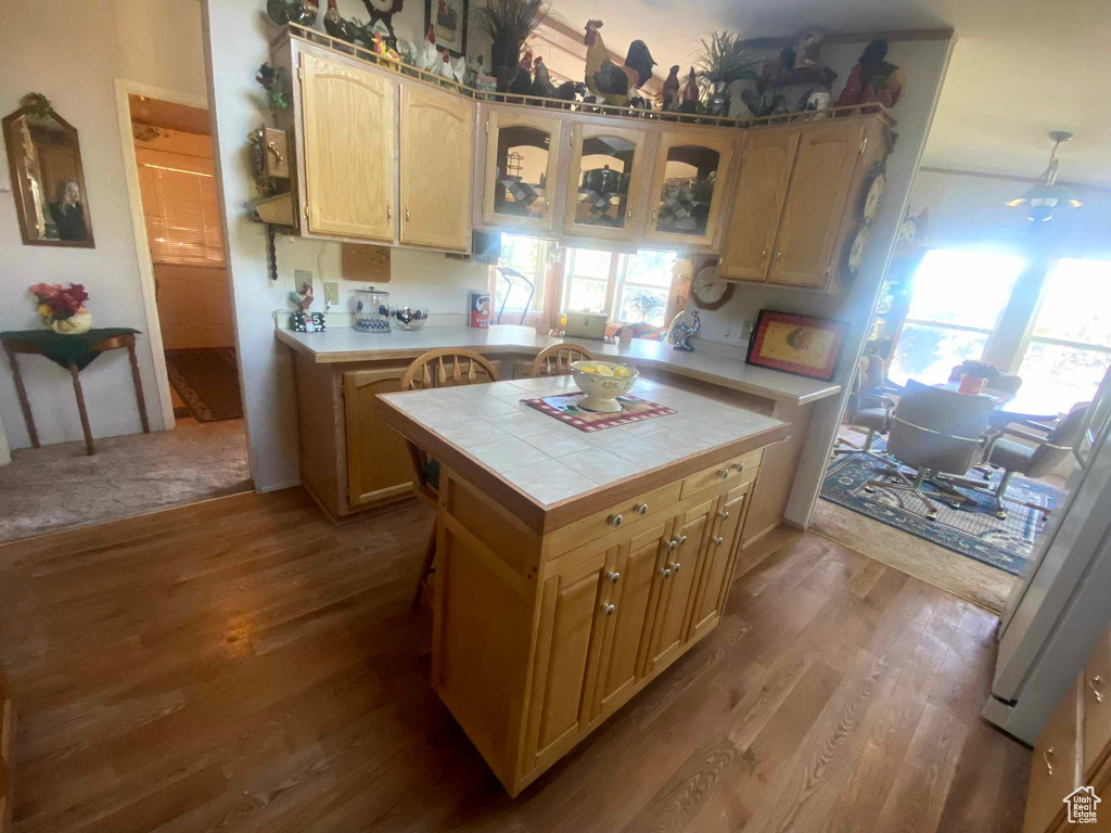 Kitchen with tile counters, hardwood / wood-style flooring, and fridge