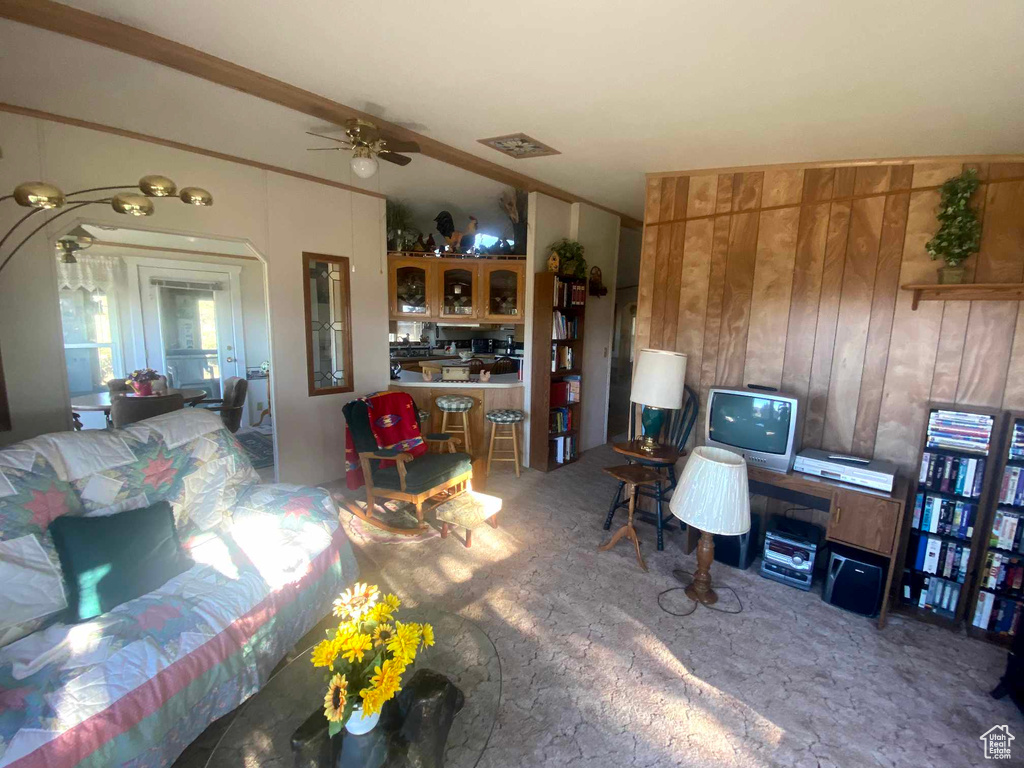 Living room with wooden walls, carpet, and ceiling fan