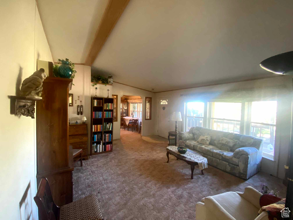 Carpeted living room featuring plenty of natural light and vaulted ceiling with beams