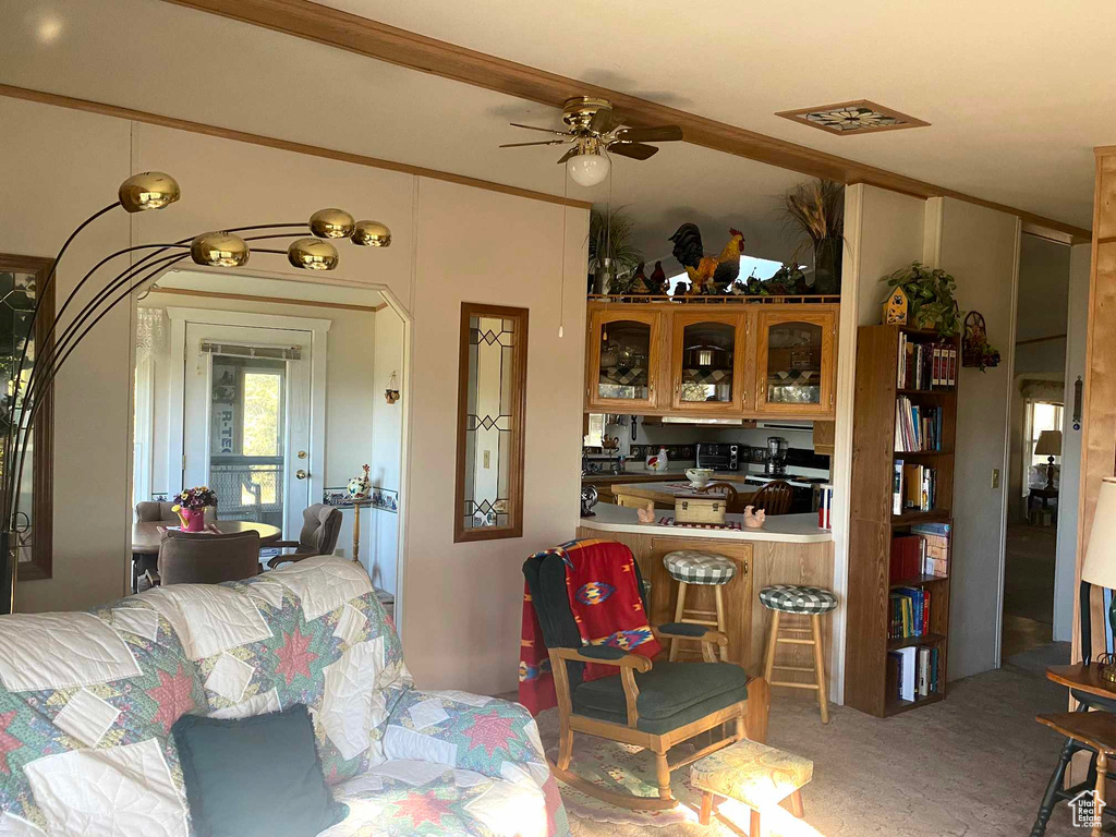 Carpeted living room featuring ornamental molding and ceiling fan