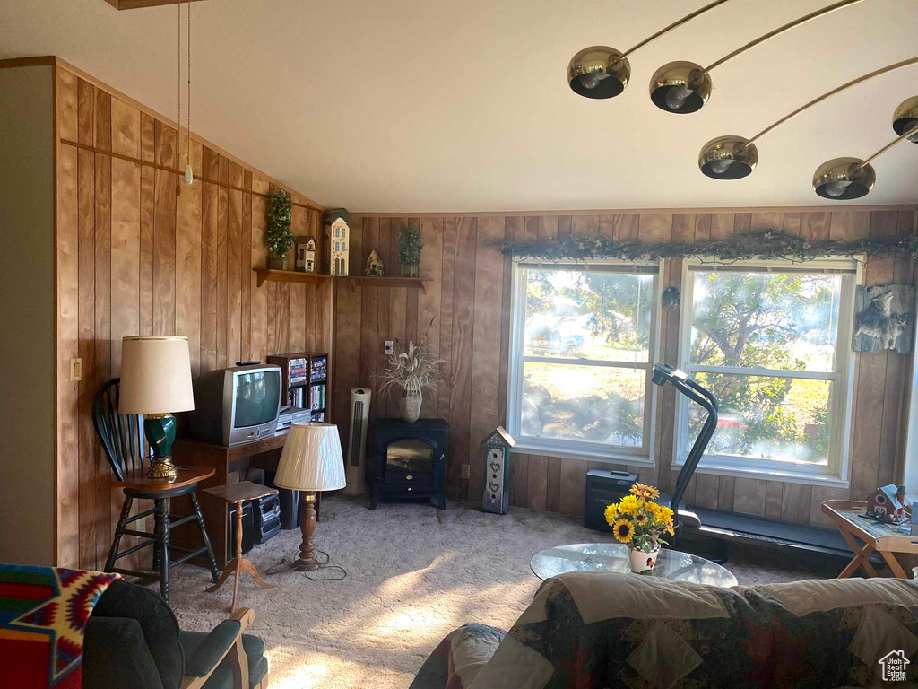 Living room with wooden walls, carpet floors, and lofted ceiling