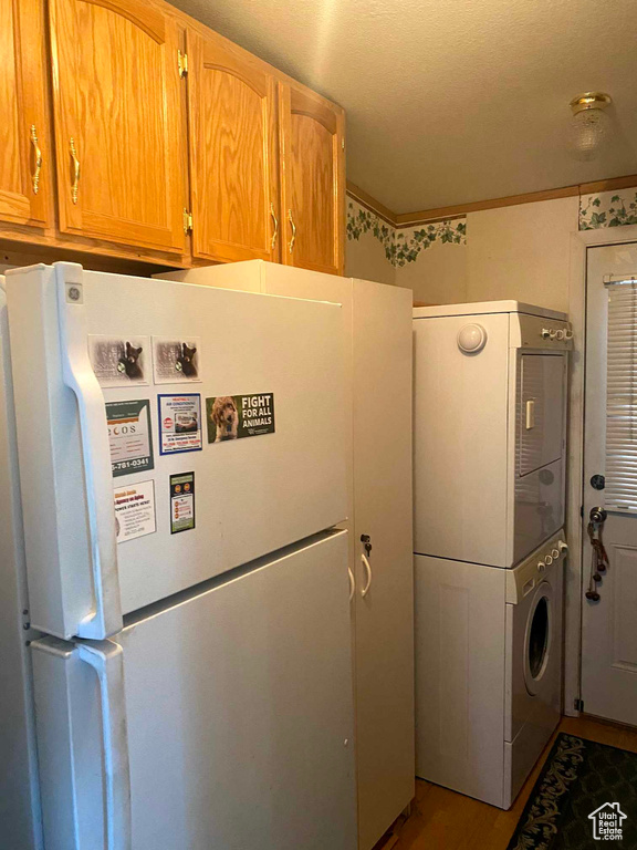 Laundry room featuring stacked washer / dryer and hardwood / wood-style flooring