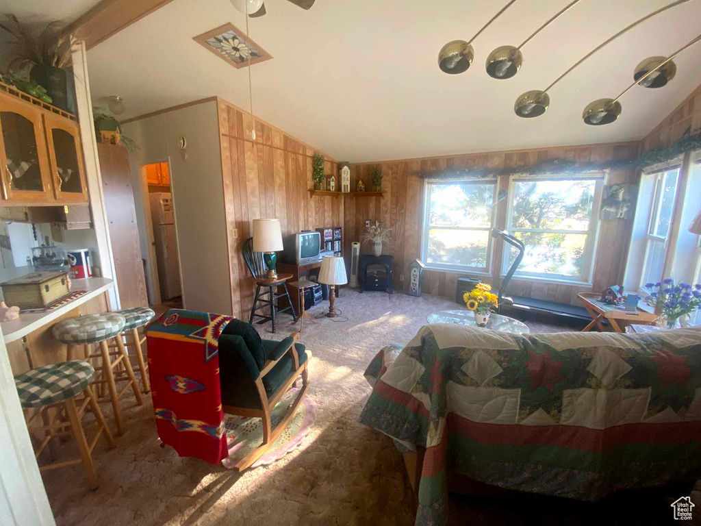 Interior space with lofted ceiling, ceiling fan, and wood walls