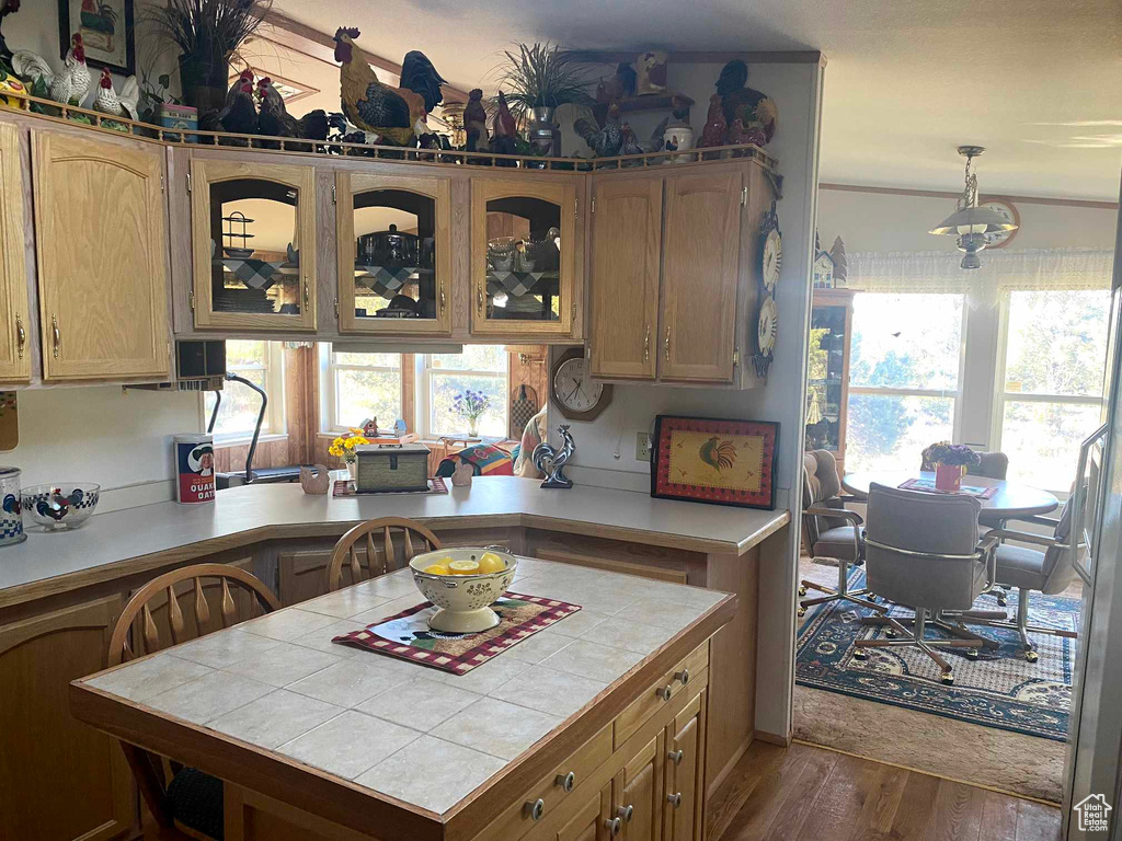 Kitchen with decorative light fixtures, hardwood / wood-style floors, tile countertops, and plenty of natural light