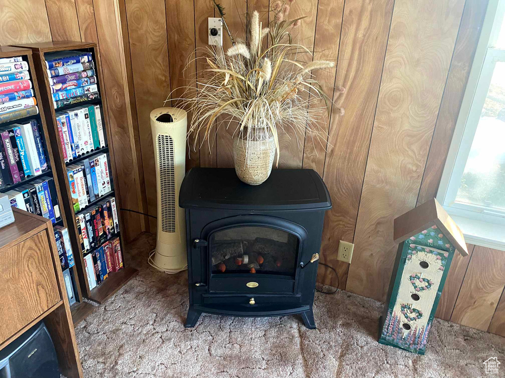 Room details featuring carpet floors, wooden walls, and a wood stove