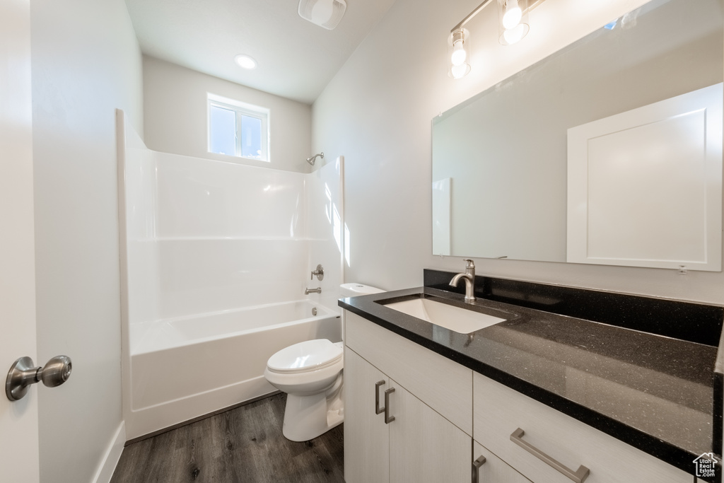 Full bathroom with hardwood / wood-style floors, bathing tub / shower combination, vanity, and toilet